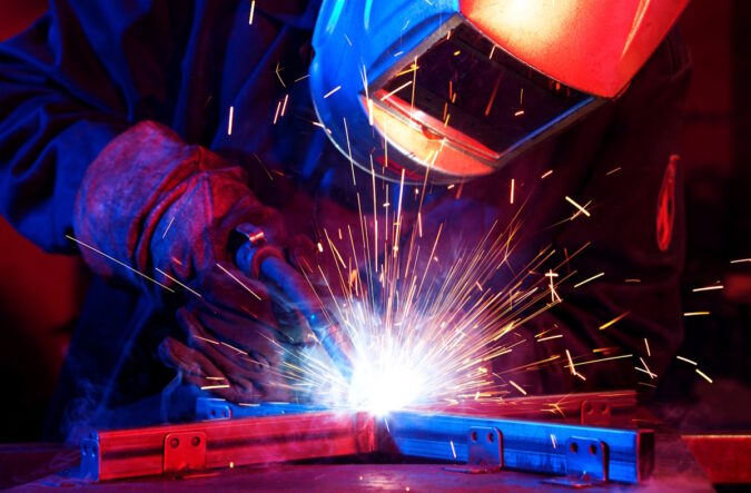 Welder erecting technical steel. Industrial steel welder in factory technical