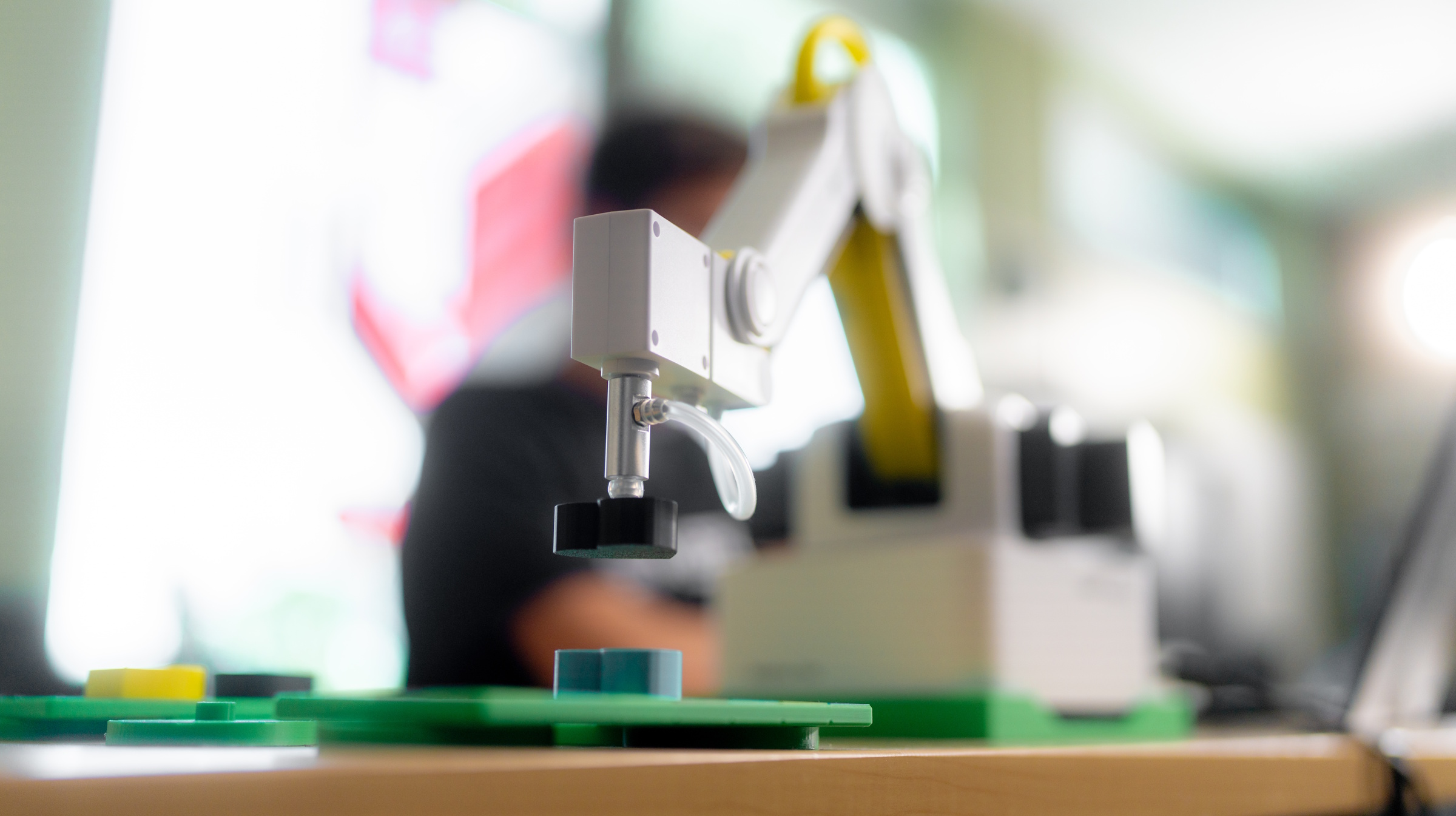 A closeup of a robotic arm attached to a desk with a blurred out background