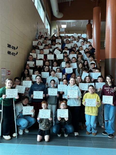A group of young students gathered along a staircase holding signs.
